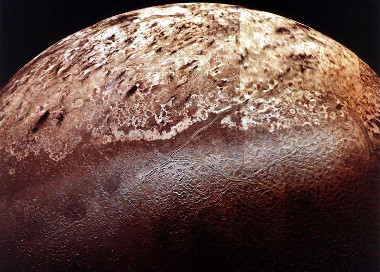 Tritão, a maior lua de Netuno. O terreno estranho ao longo do centro da imagem é chamado