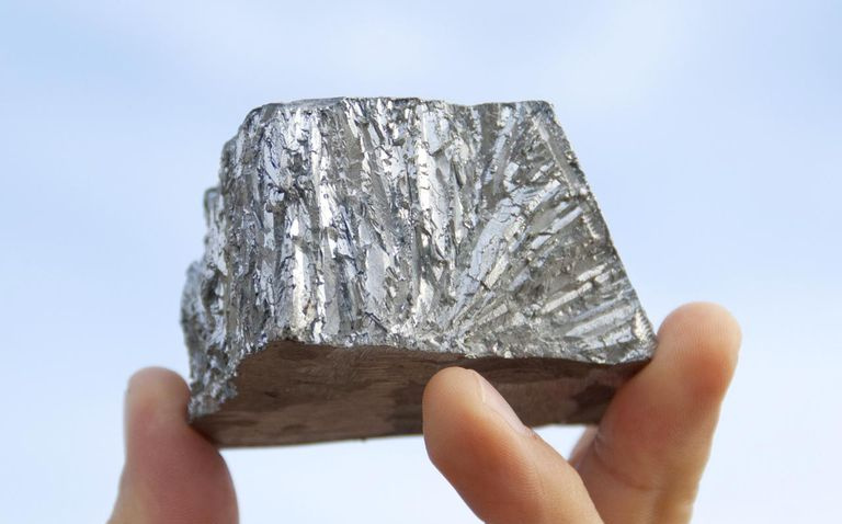 Mão segurando metal de zinco puro