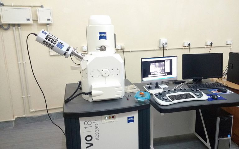 Elektronmikroskops un datortehnika laboratorijas vidē.