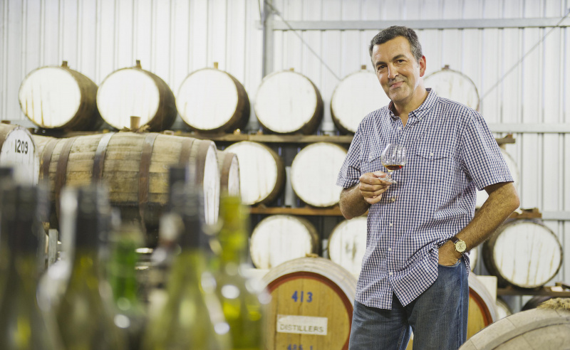 Uomo in una cantina con botti di vino