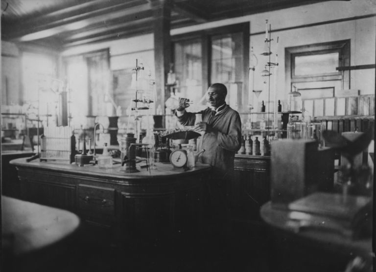 Svart-hvitt-bilde av George Washington Carver som jobber i laboratoriet hans.