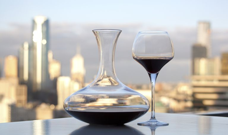 Decanter per vino e bicchiere seduti su un tavolo con uno skyline della città sullo sfondo.