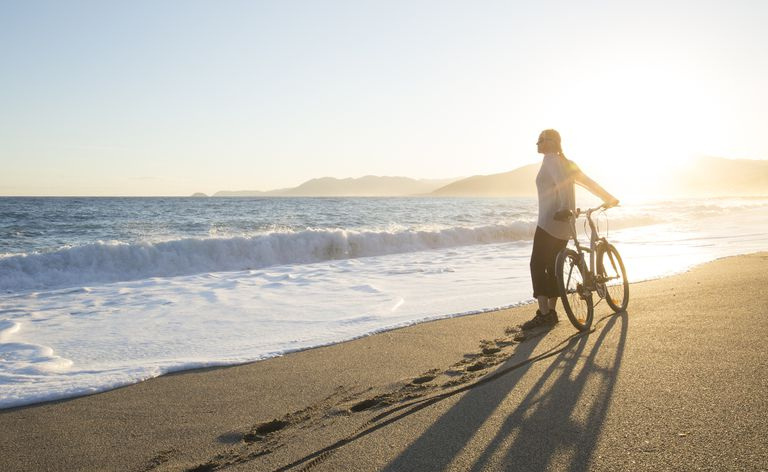 Ciclista feminina em uma praia ao nascer do sol