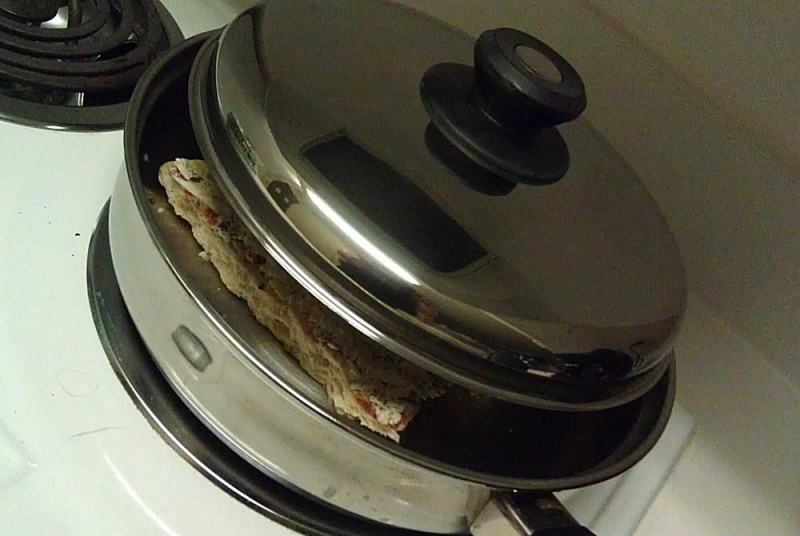 Zamrożoną pizzę umieść na patelni i przykryj pokrywką.