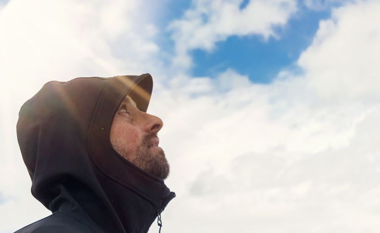 Homem olhando para o céu com sol