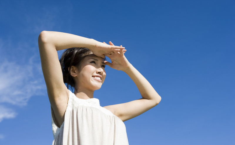 Uma mulher protege os olhos da luz do sol para ver à distância