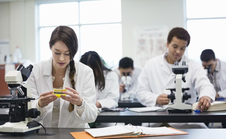 科学実験室で顕微鏡を持つ学生。