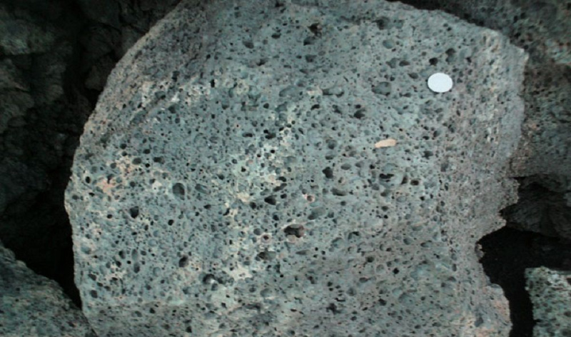 Pezzo di basalto vescicolare con quarto americano posizionato sopra.