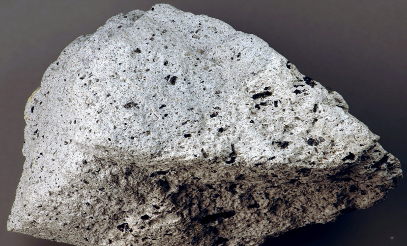 Grande pezzo di roccia andesite su sfondo grigio.