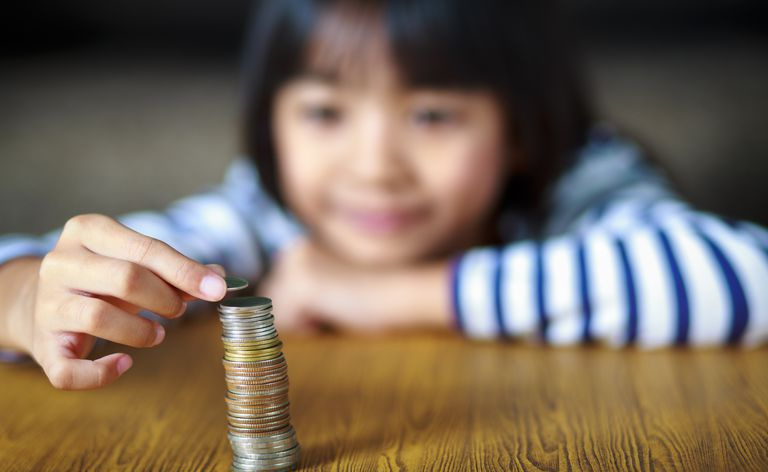 criança com pilha de moedas