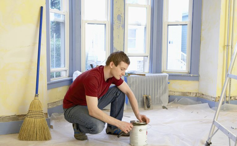 Mann, der eine Farbdose mit einem Hebel öffnet.