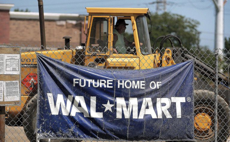 Un panneau annonçant un nouveau Wal-Mart est suspendu à une clôture grillagée près du projet de construction