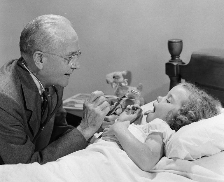 1950. gadu fotogrāfija, kurā redzams ārsts, kurš izmeklē slimu meiteni