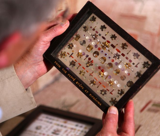 Der Autor Charles Allen untersucht Originaljuwelen von Piprahwa Stupa