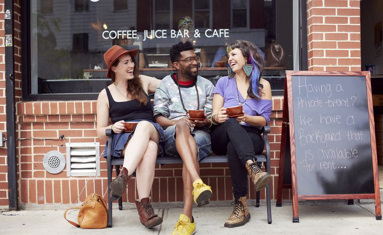 Eine Gruppe junger Leute lacht vor einem Café