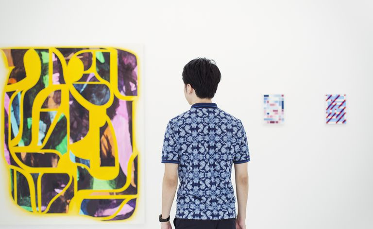 Um homem em uma galeria de arte observa arte abstrata.