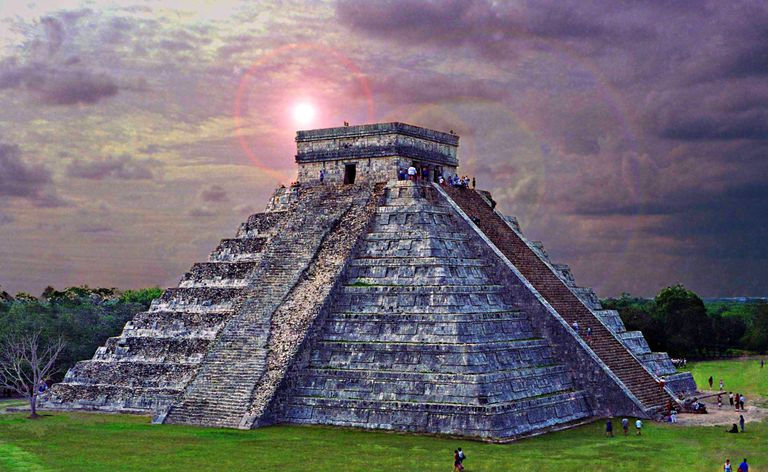 Chichén Itzá ao entardecer, com nuvens roxas intensas e muitos turistas ao redor do edifício