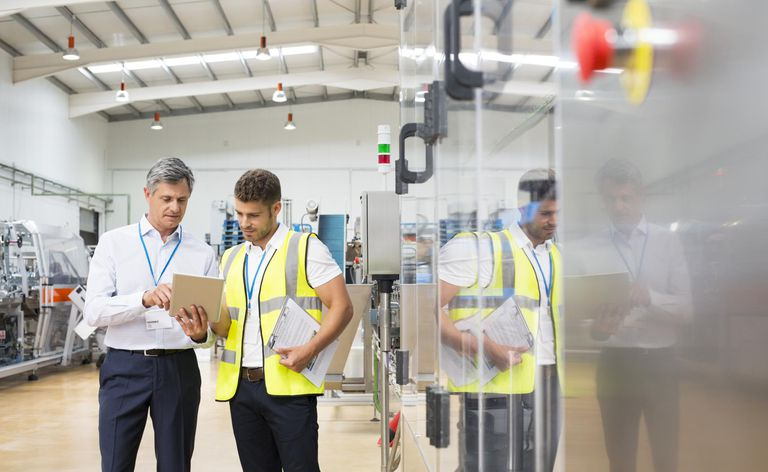 Veileder og arbeider som bruker digitalt nettbrett på fabrikken