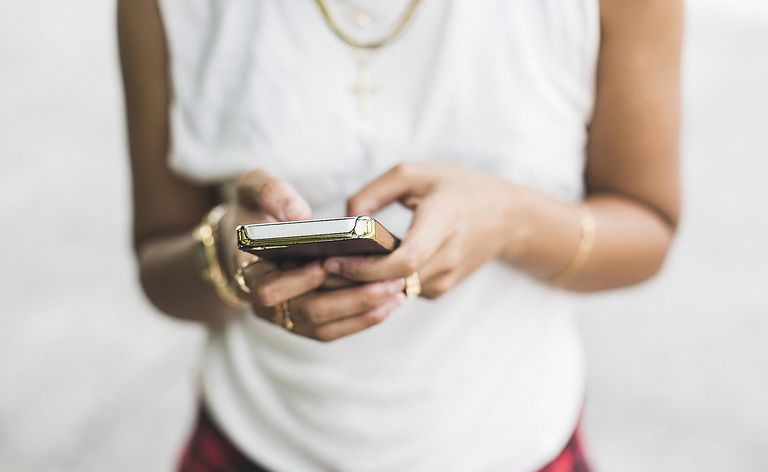 Kobieta trzyma w rękach telefon komórkowy.
