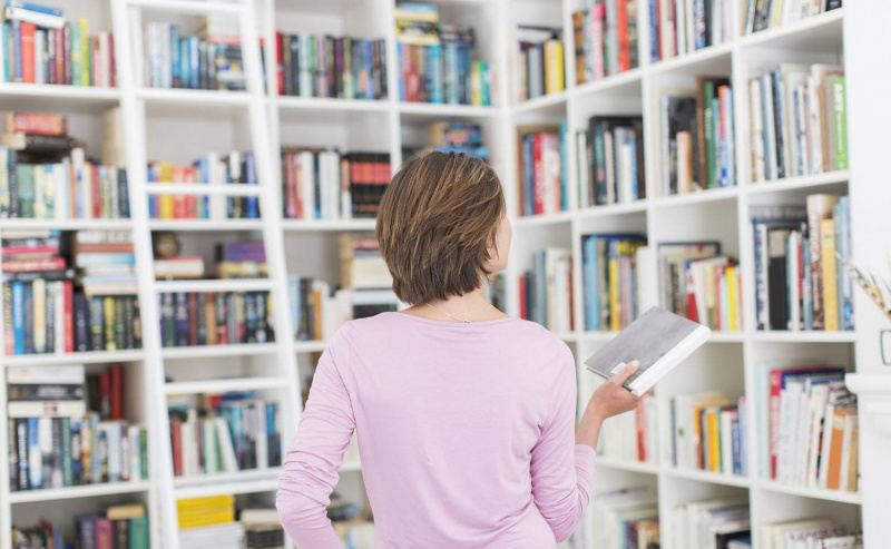 Kvinne velger bok fra biblioteket