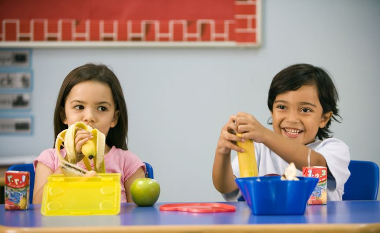 Ein Junge und ein Mädchen beim Mittagessen in einem Klassenzimmer.