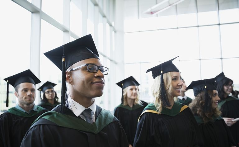 Orgullosos graduados universitarios toga y birrete mirando a otro lado