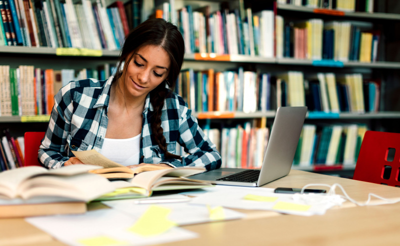Estudiante leyendo libro y tomando notas para estudiar