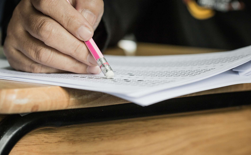 estudiante sosteniendo un borrador de lápiz mientras toma un examen