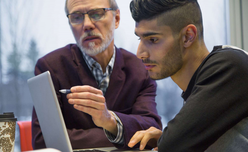 Professor og høyskolestudent ved laptop