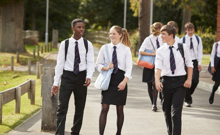 Grupo de estudiantes adolescentes en uniforme fuera de los edificios escolares