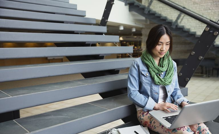 Kvinnelig student sitter på tribune med laptop