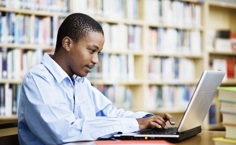Uno studente maschio che lavora a un computer portatile in una biblioteca del college
