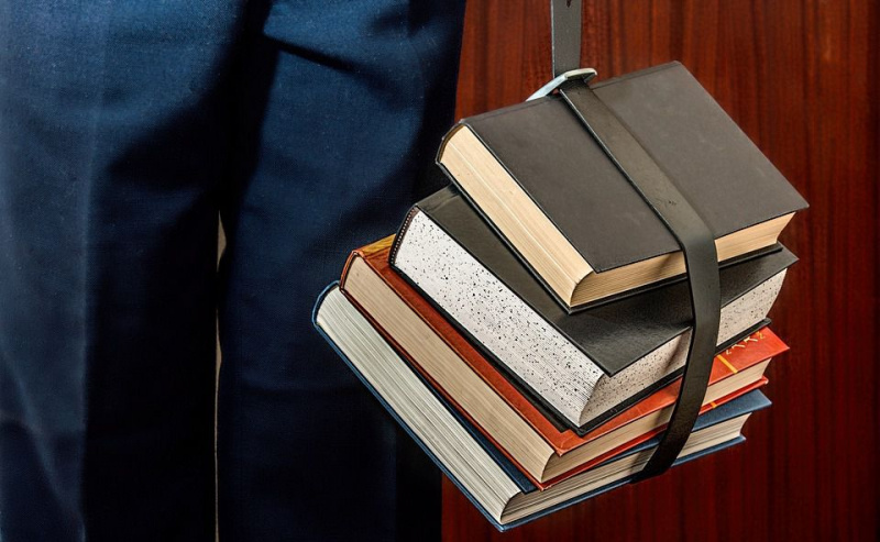 students, kurš nes grāmatas siksniņā