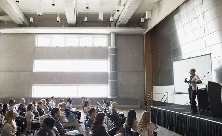 Alunos na plateia do auditório assistindo o professor no palco