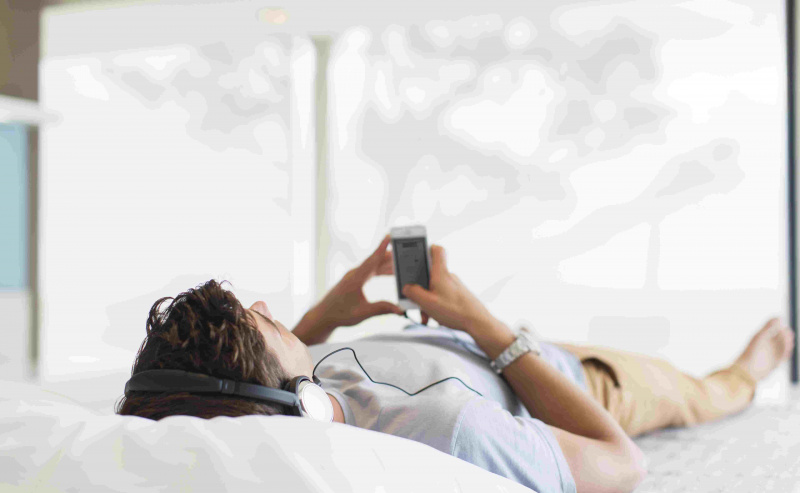 Uomo che ascolta la musica mentre è sdraiato sul letto
