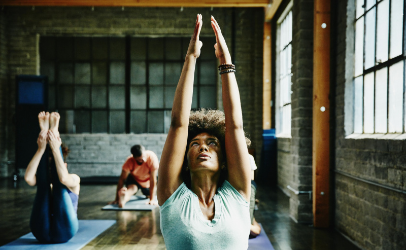 Donna in fase di riscaldamento per la lezione di yoga in studio