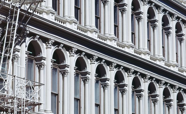 Detail der verzierten gusseisernen Fassade mit Bögen über jedem Fenster, eingelassenen Säulen, die von den Fensterseiten hervorstehen, und einer Balustrade unter jedem Fenster