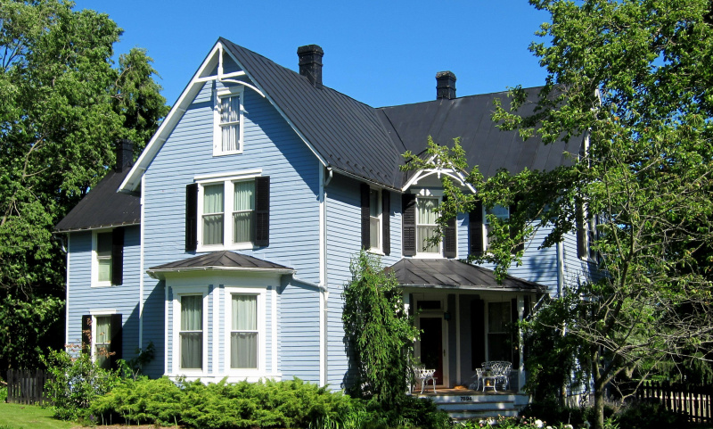 Ein schickes Bauernhaus mit blauen Seitenwänden, Erker und Eingang im Kreuzgiebel