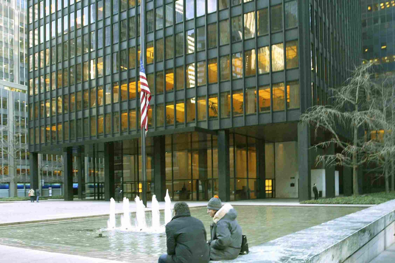 Zwei Menschen sitzen an einem Pool vor einem Wolkenkratzer, der von den Straßen von New York City zurückversetzt ist