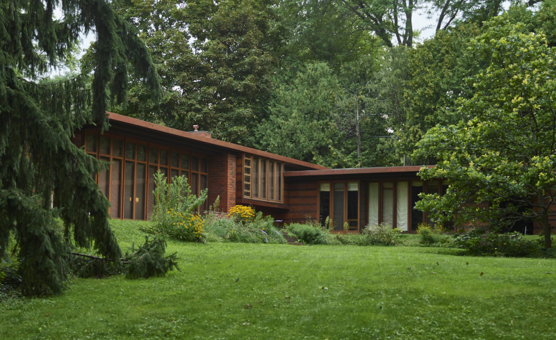 petite maison moderne horizontale semblable à un ranch de verre et de bois verticaux dans un cadre boisé