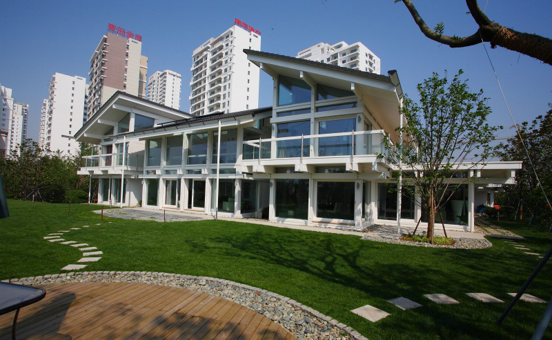 Dom Huf Haus w Chinach, wieżowce mieszkalne w tle, drewniane patio na pierwszym planie