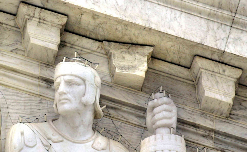 Der gebrochene Zahn und das Netz um Statuen auf dem Gebäude des Obersten US-Gerichtshofs