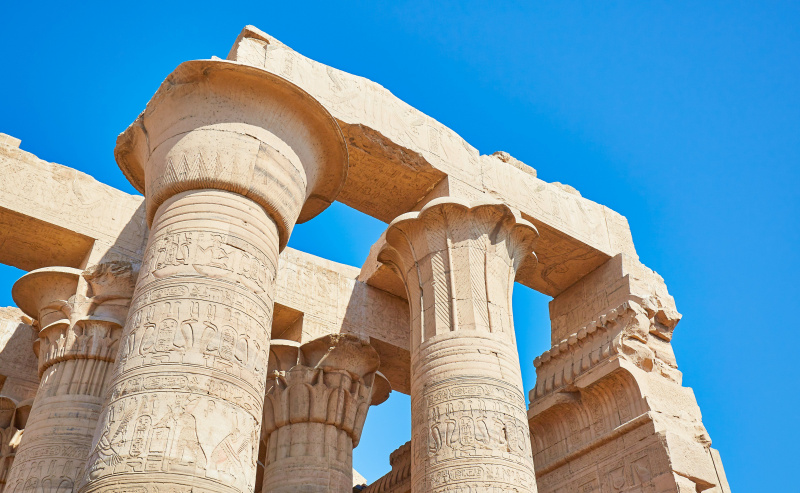 vista en ángulo bajo de los antiguos capiteles de las columnas, mirando hacia un cielo azul brillante