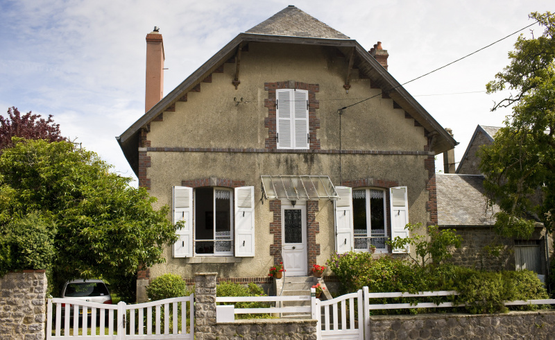 casa de piedra de dos pisos con techo de caballete, puerta central, persianas blancas, decoración quoin