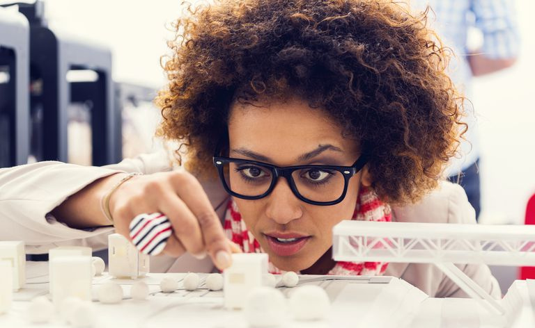 Nahaufnahme eines jungen Architekten, der in einem 3D-Druckerbüro sitzt und sich 3D-Drucke ansieht